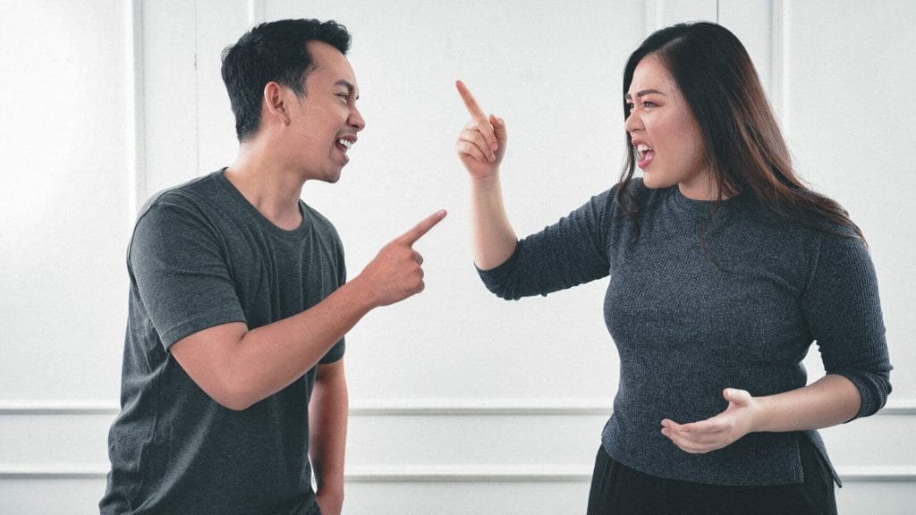 A man and woman arguing while pointing fingers